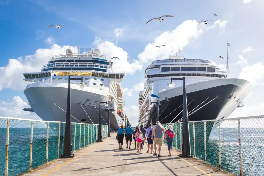 Group of people heading toward two cruise ships docked at a sunny port