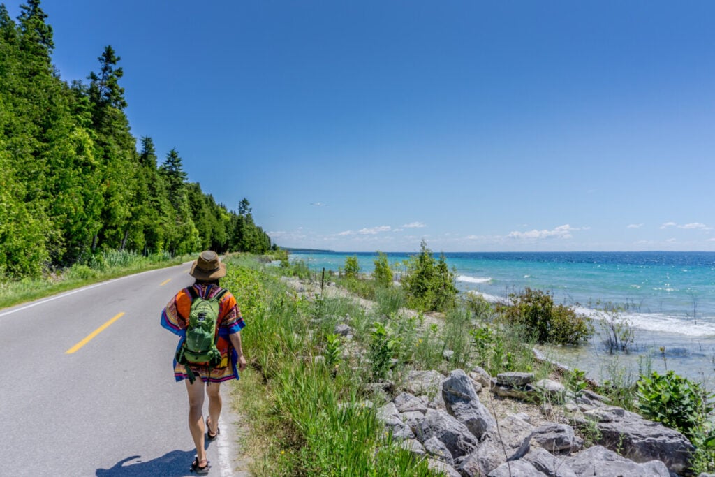 A woman walks along a road by lake huron