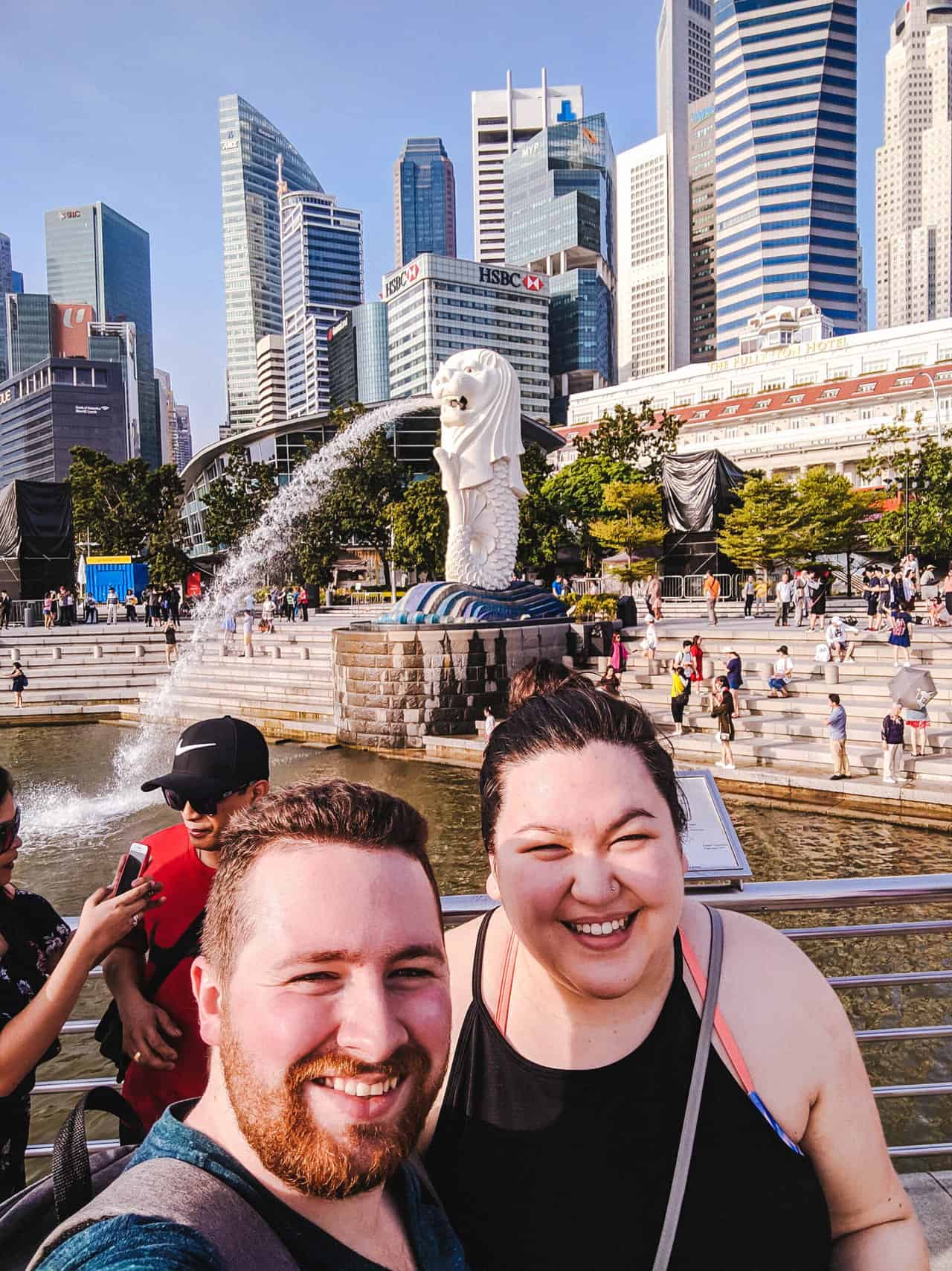 Selfie of Colin and Riana in front of a merlion statue in Singapore by the water