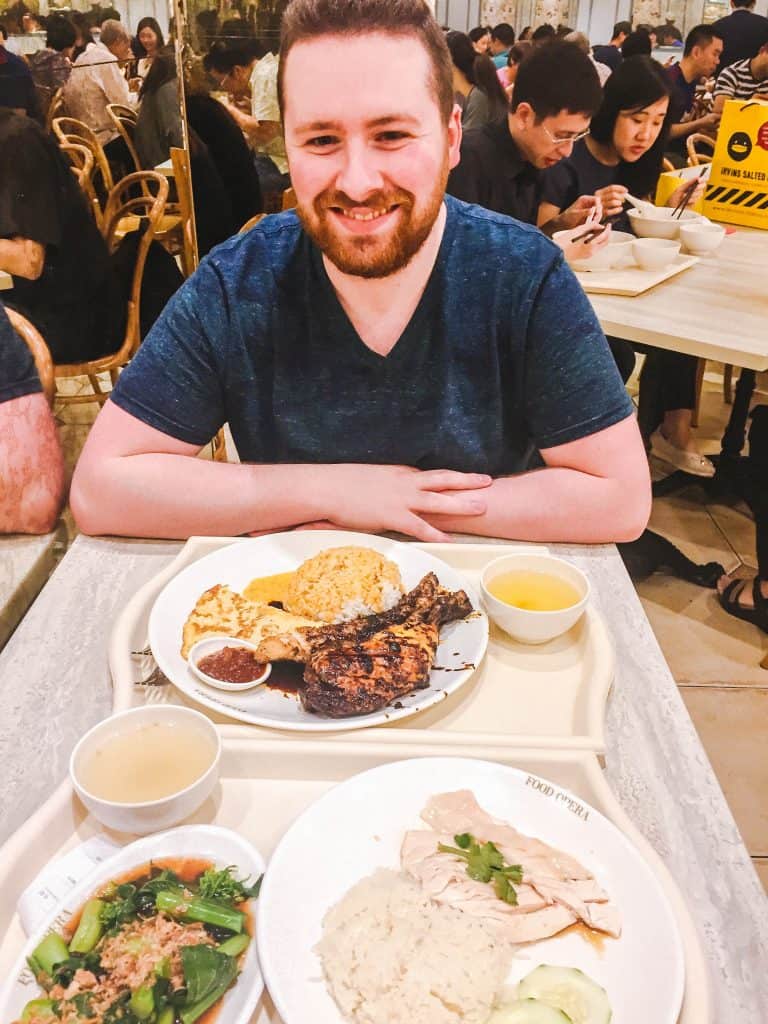 Colin posing with our meals from the mall food court in Singapore featuring chicken and rice 