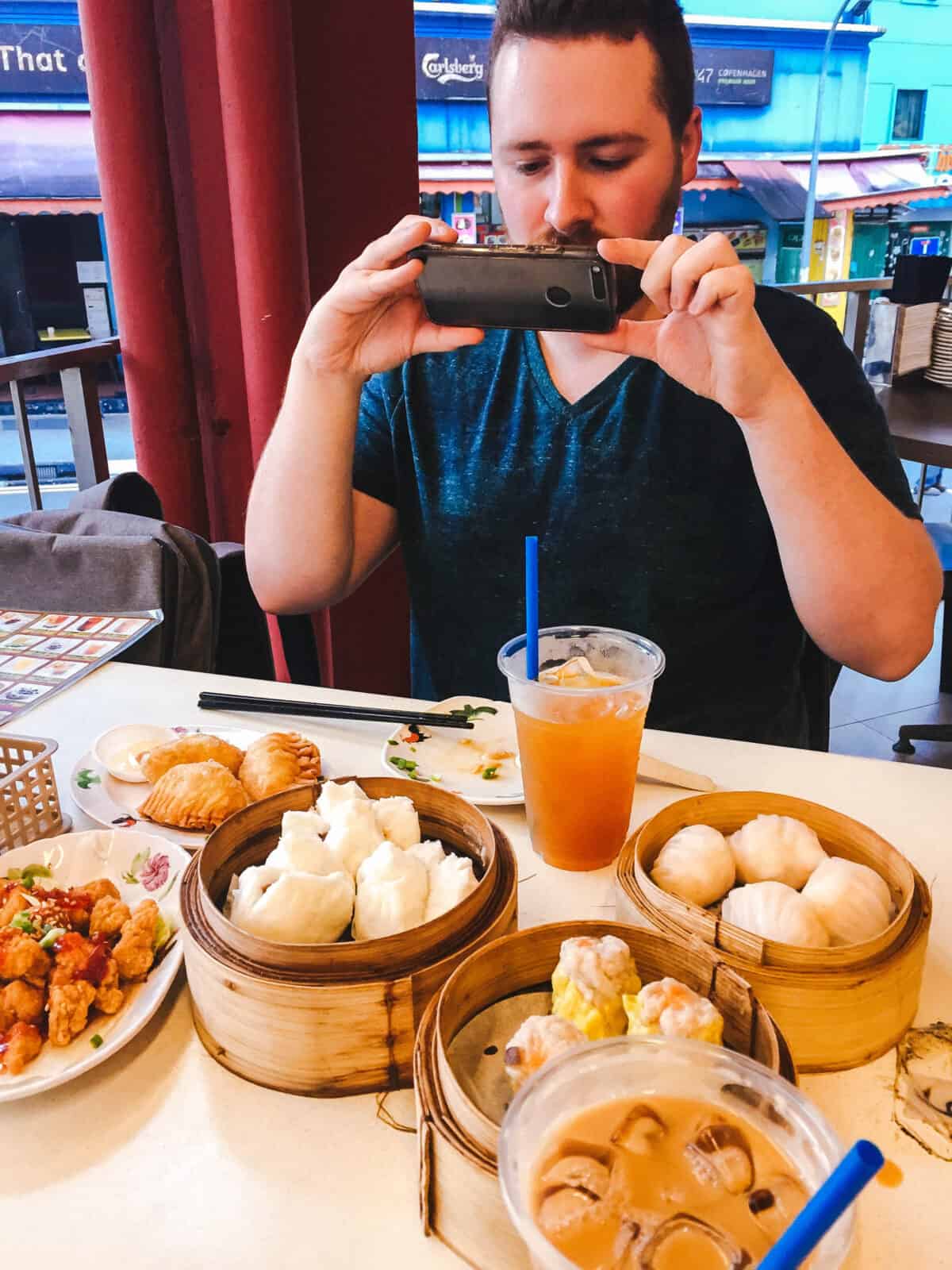 Colin taking a picture of a table full of dim sum in Singapore