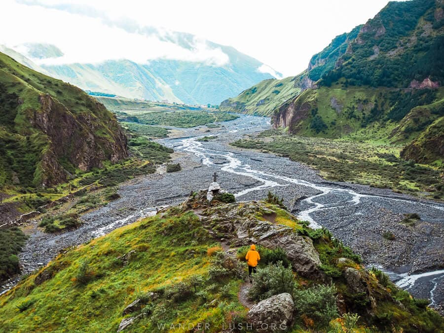 A person walks to the edge of a mountain cliff in Dariali Gorge, Georgia.