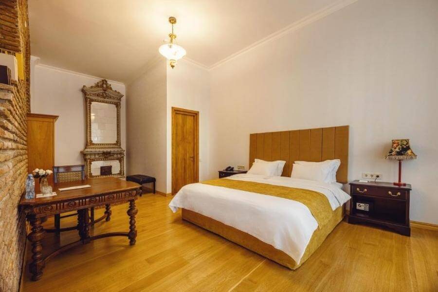 A hotel room with mustard wood floors and a vintage fireplace.