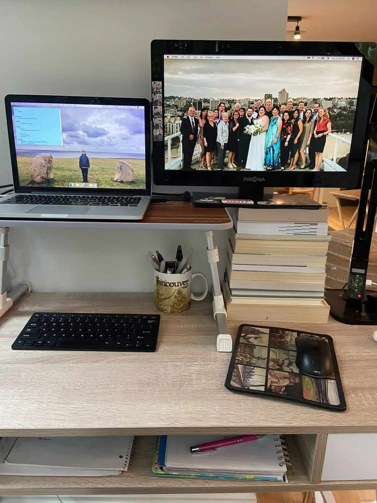 Two screens on Riana's desk, one is a laptop on a riser and the other is a monitor supported on a stack of books