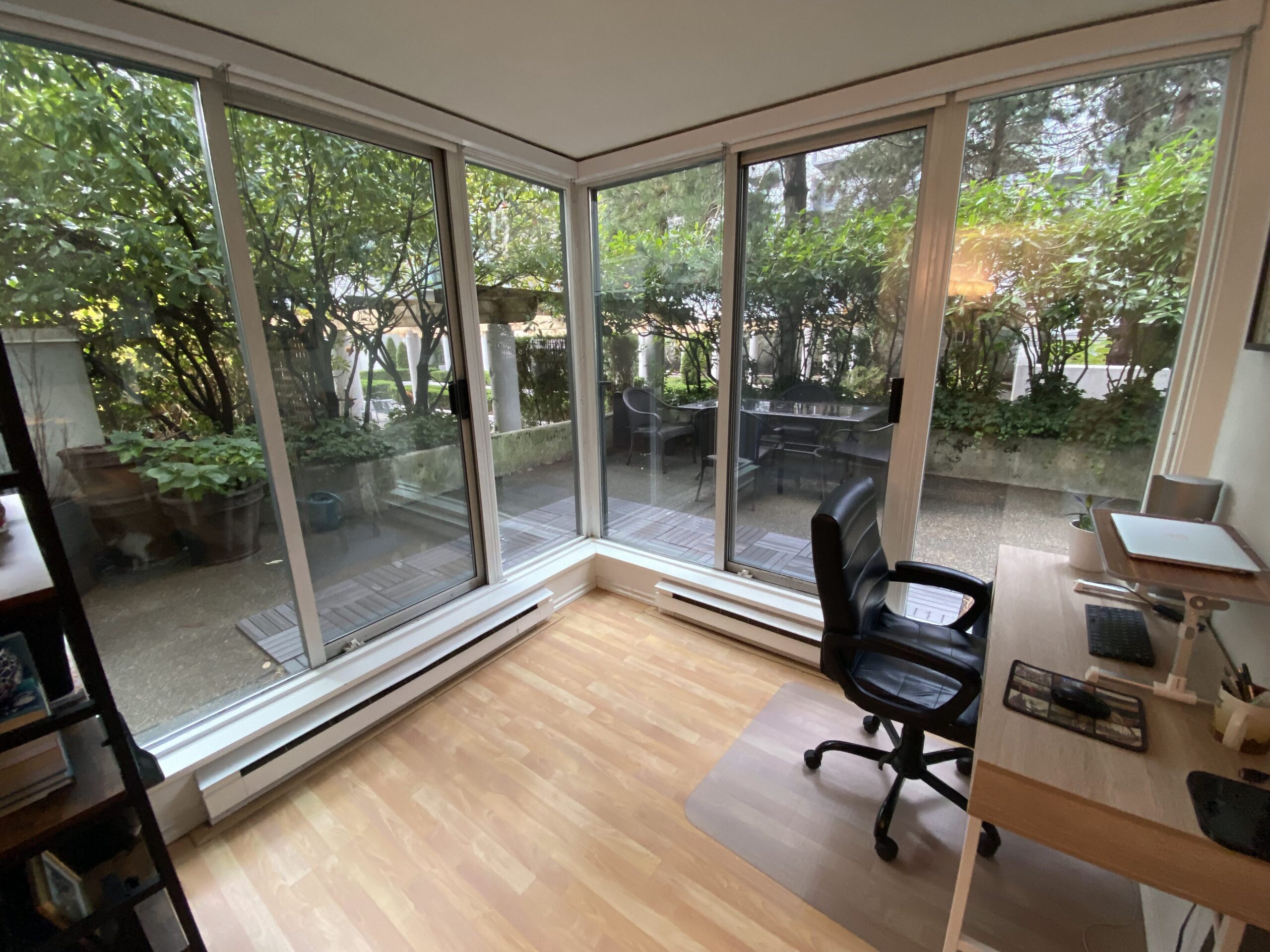 Freelancer office in 2022 with glass walls on all sides around a shelf, desk and computer chair