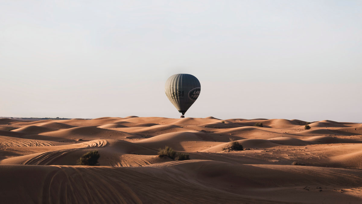 A hot air balloon glides across sand dunes in the desert outside Dubai.