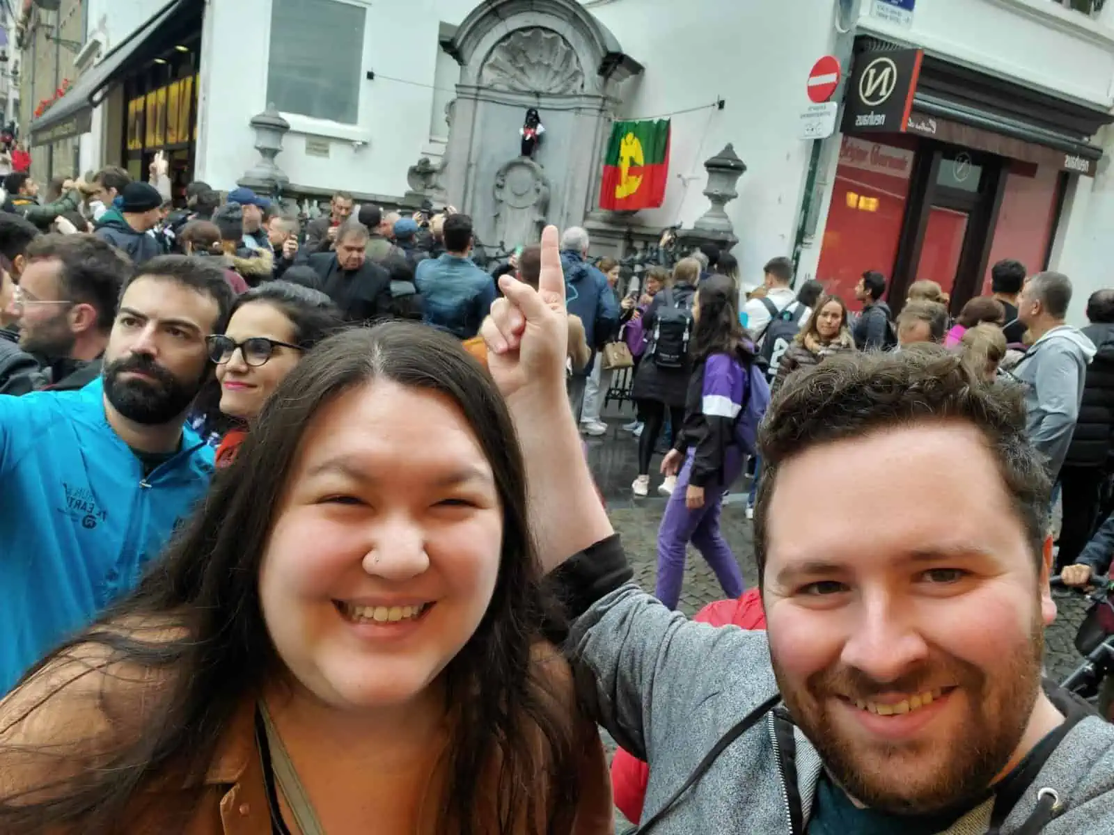 Colin and Riana taking a selfie with manneken pis in brussels, belgium