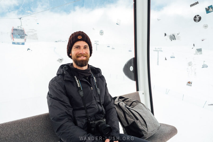 A man in a beanie sits inside a moving gondola in Gudauri, Georgia.