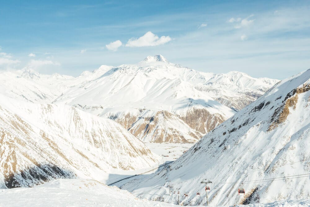 A cable car line runs through a valley beneath Mount Kazbek in the country of Georgia.