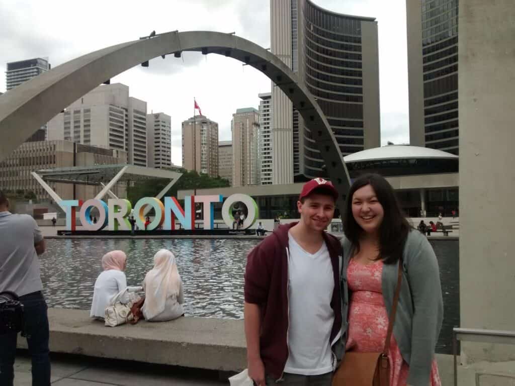 Colin and Riana posing in front of the Toronto sign at Nathan Phillip Square in 2015