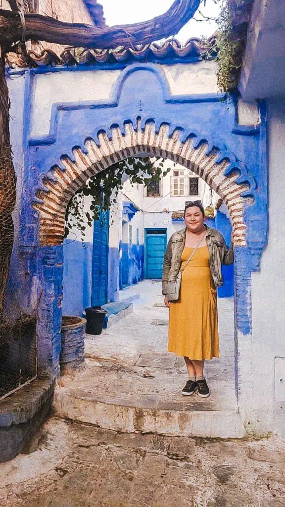 Riana standing in front of a blue arched doorway in Chefchaouen Blue City Morocco