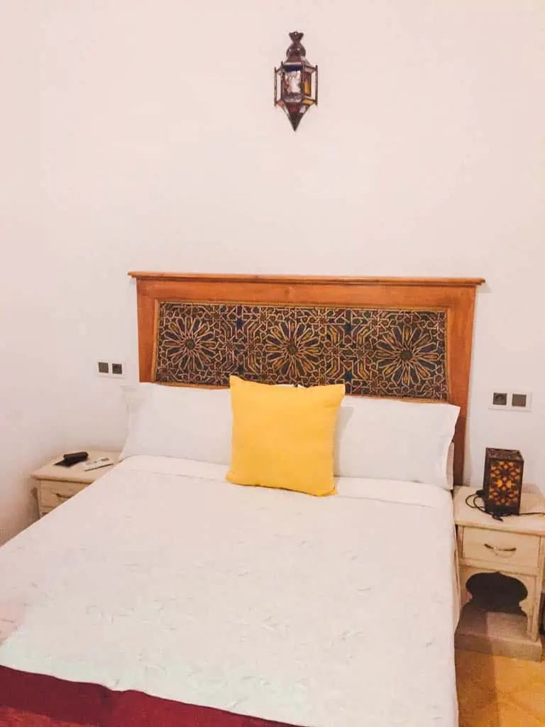 Bedroom at Hotel Honeysuckle riad in Chefchaouen with a bed with white sheets and a yellow pillow