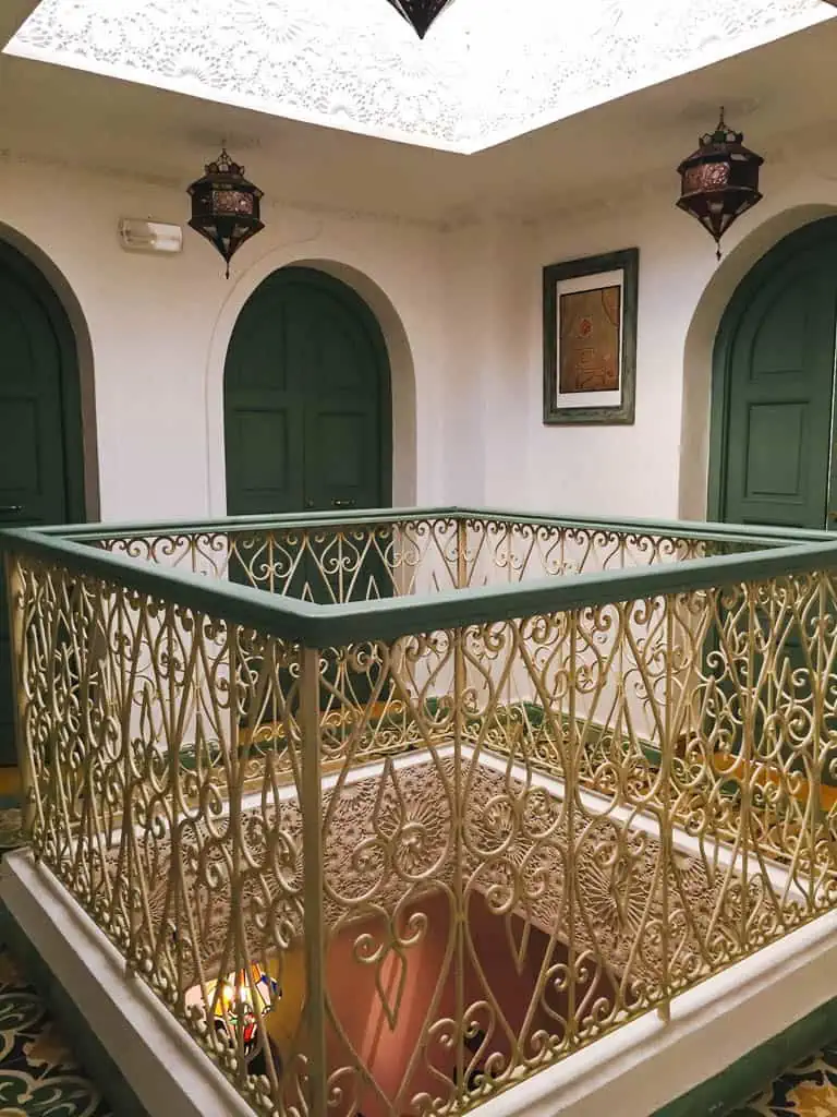 Hallway in Hotel Honey Suckle riad in Chefchaouen with green doors and a green bannister with gold trim