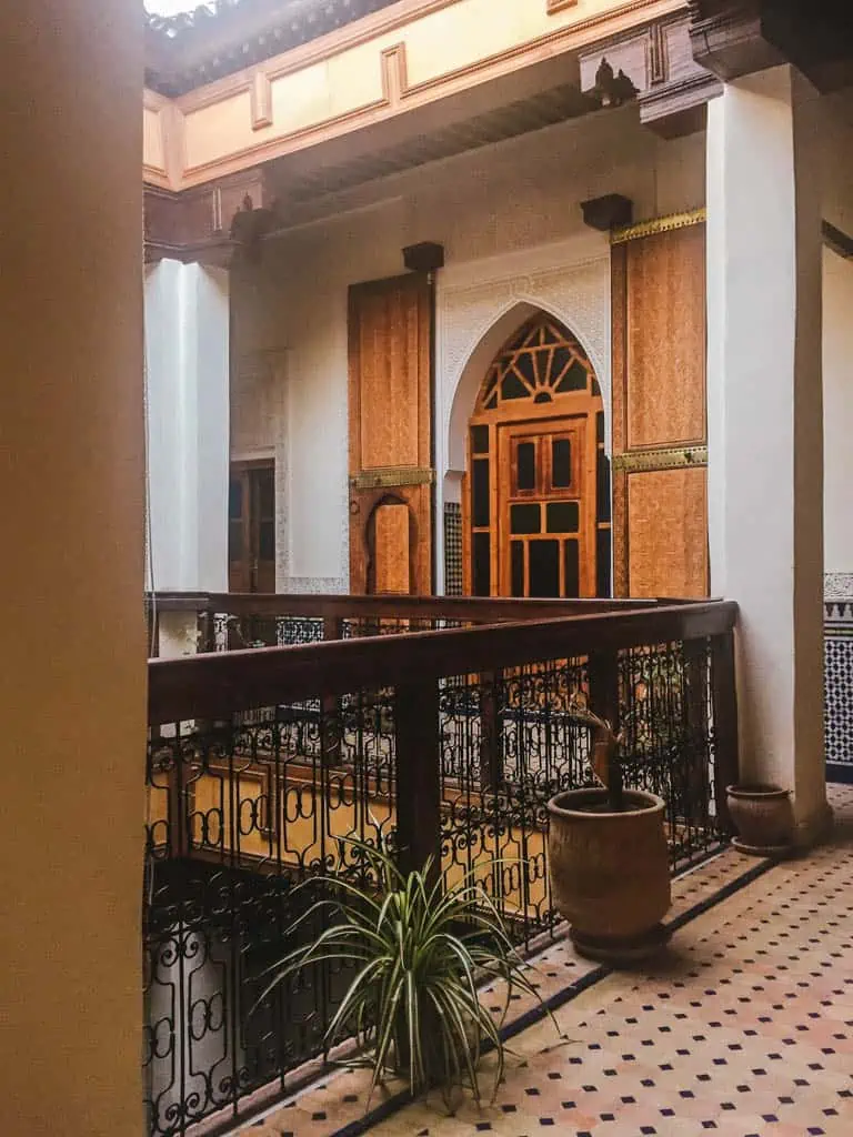 Hallway at Riad Taryana in Fes, Morocco with an arched door, columns and railing