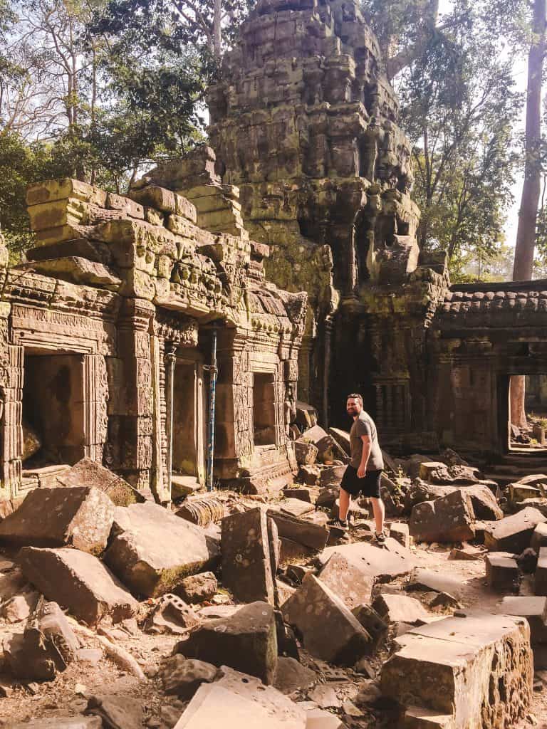 Colin walking on rubble while he explores Ta Prohm at Angkor Wat in Siem Reap, Cambodia