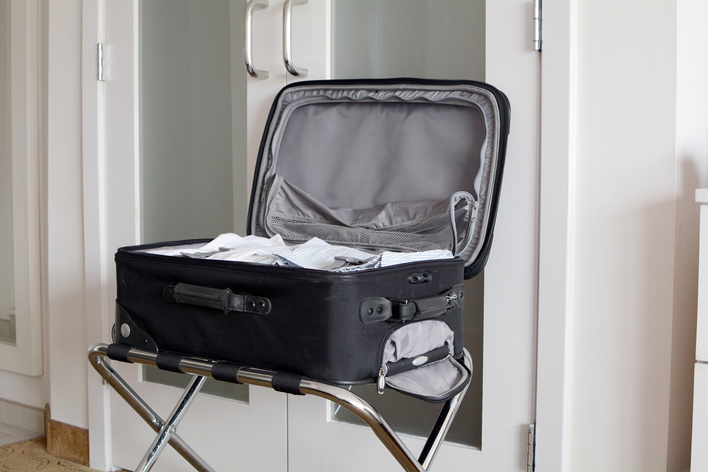 Luggage rack with black suitcase open on top of it