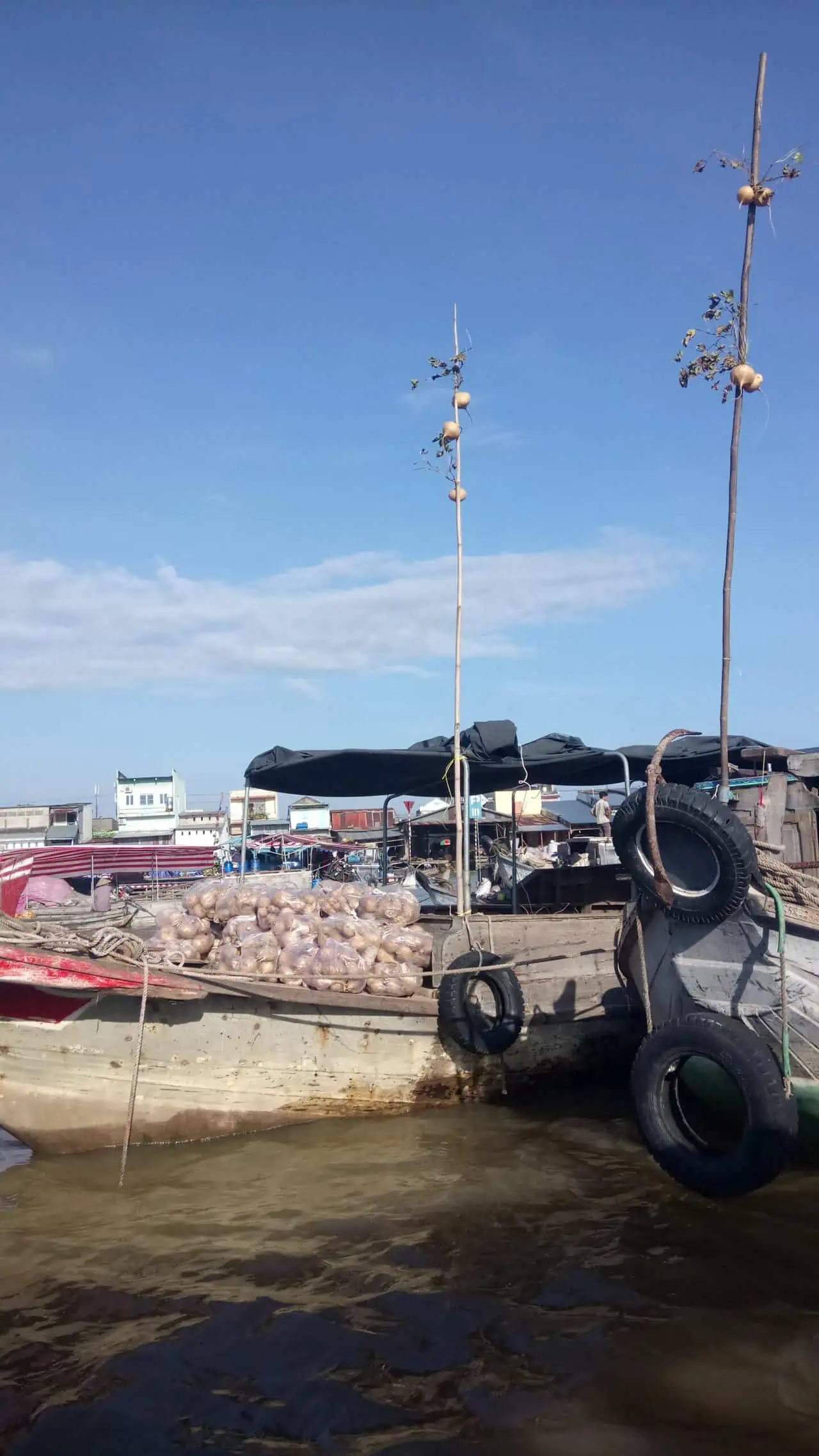 A vendor boat floating on the Mekong Delta selling turnips with a turnip hanging up on the mast