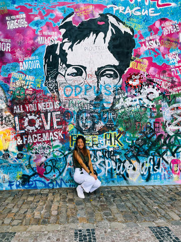 University of Massachusetts student Jessie crouches in front of the John Lennon Wall located in Old Town Prague