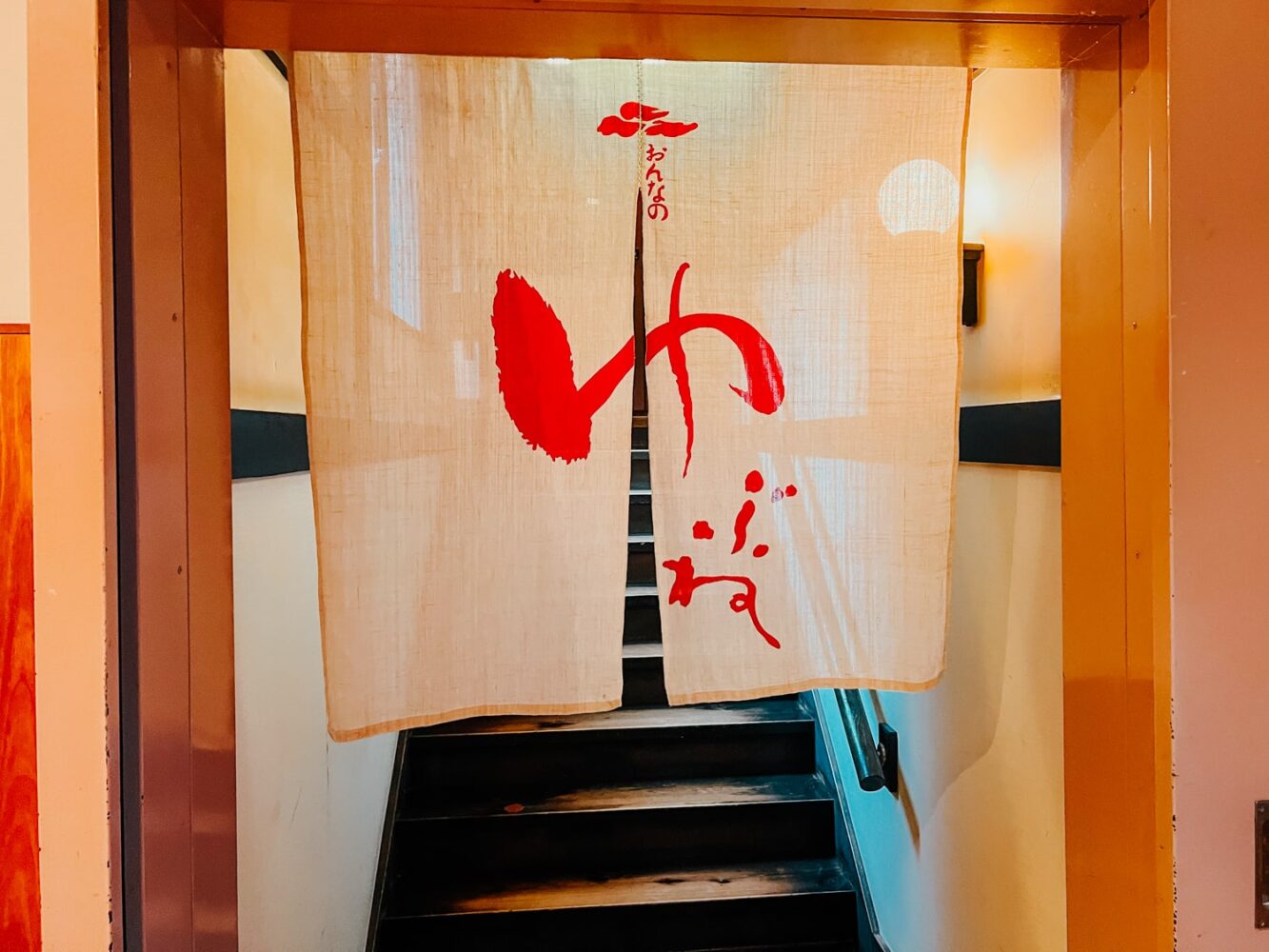 A drape with red lettering marking the entrance to the women's side of the Tenzan tattoo-friendly onsen in Hakone.