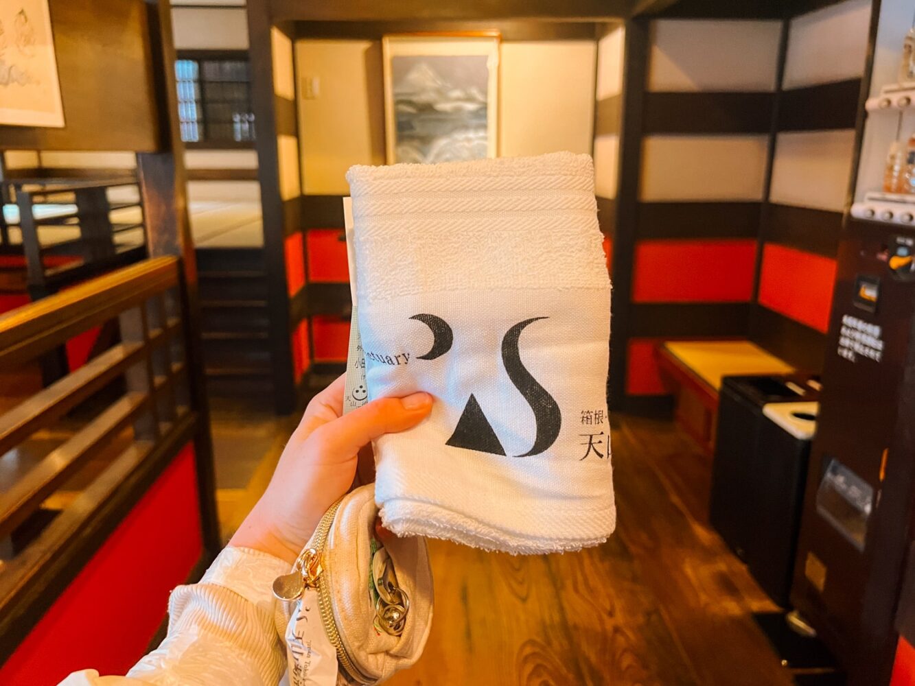 Women holding a small onsen rental towel inside traditional Japanese ryokan.