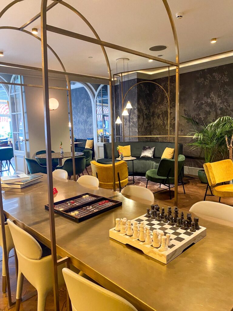 Luxurious bar and lounge area at Tivoli Doelen Hotel in Amsterdam, featuring chic furniture, golden accents, and a prominent chessboard on a table.