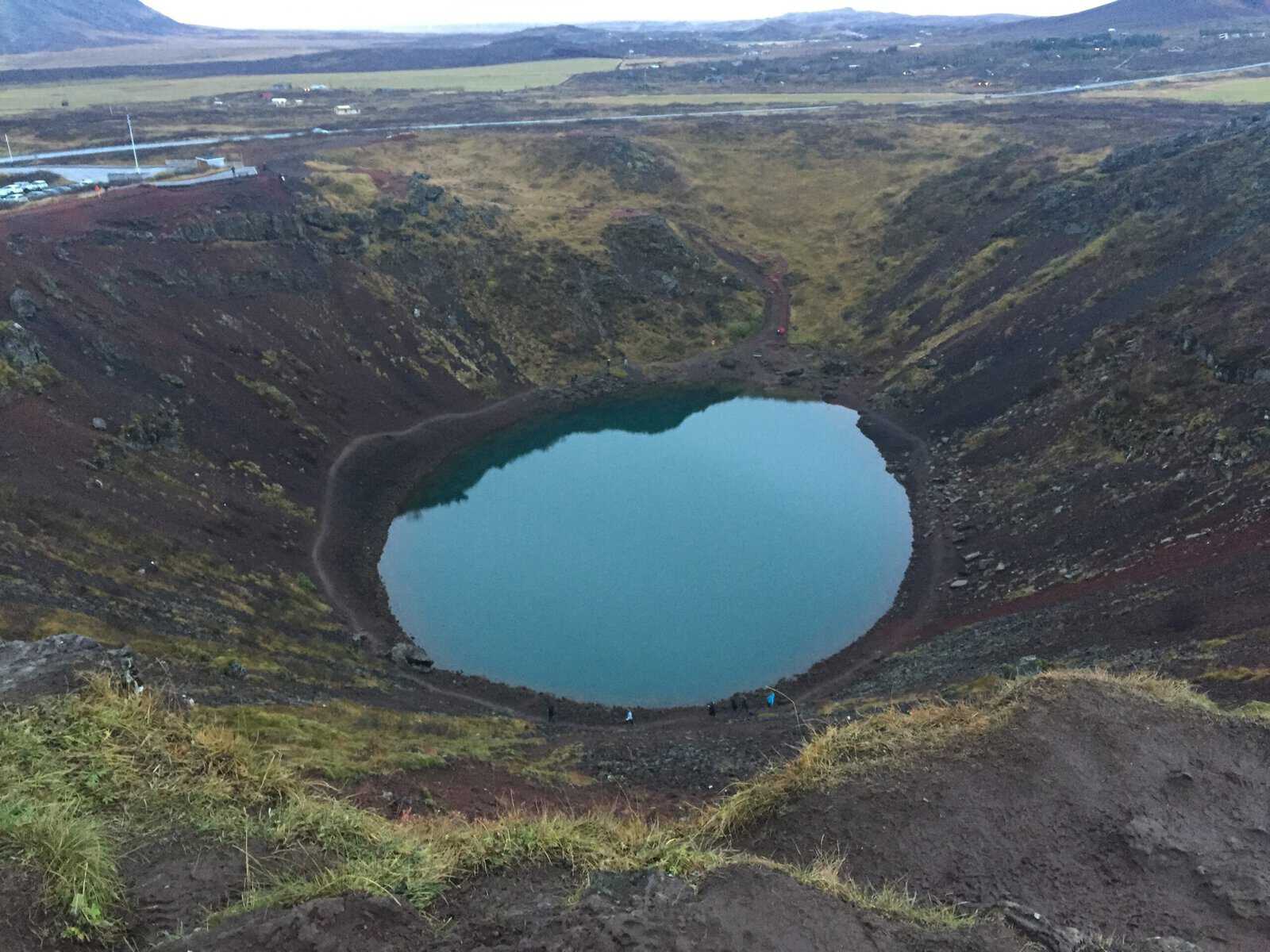 Wide shot of the Kerid Crater in Iceland looking at the sloping walls down to the turquoise blue pool 