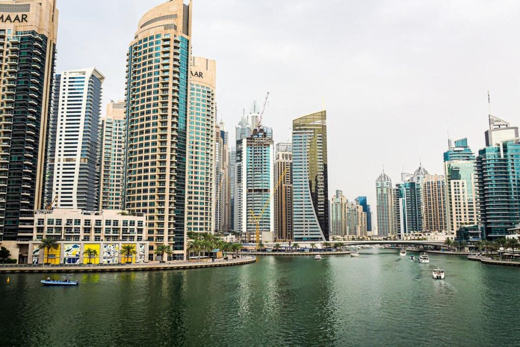 A panoramic view of the Dubai Marina waterfront with modern skyscrapers and leisure boats.