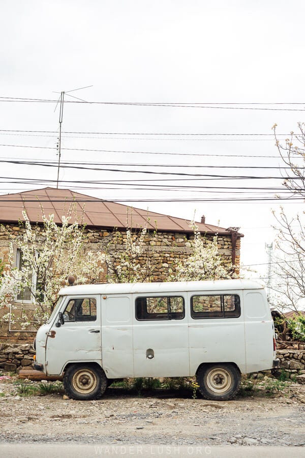 An old Soviet Buhanka truck parked on the side of the road in front of a blossoming tree in Kakheti.