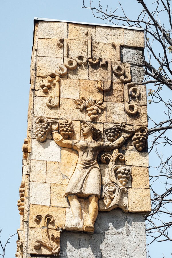 A Soviet-era sign for the village of Vazisubani with a woman and grapes.