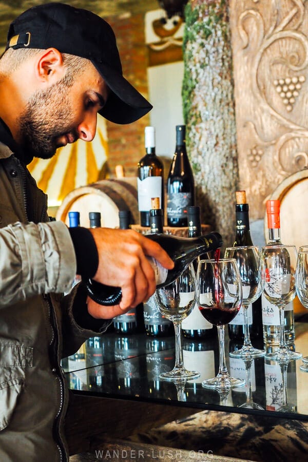 A man pours red wine into a glass at a wine degustation at Ampelo in Kakheti.