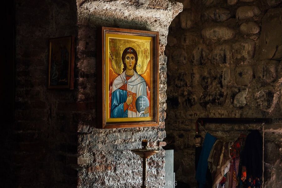 An illuminated icon hanging on a stone wall inside Gurjaani Kvelatsminda monastery in Kakheti.