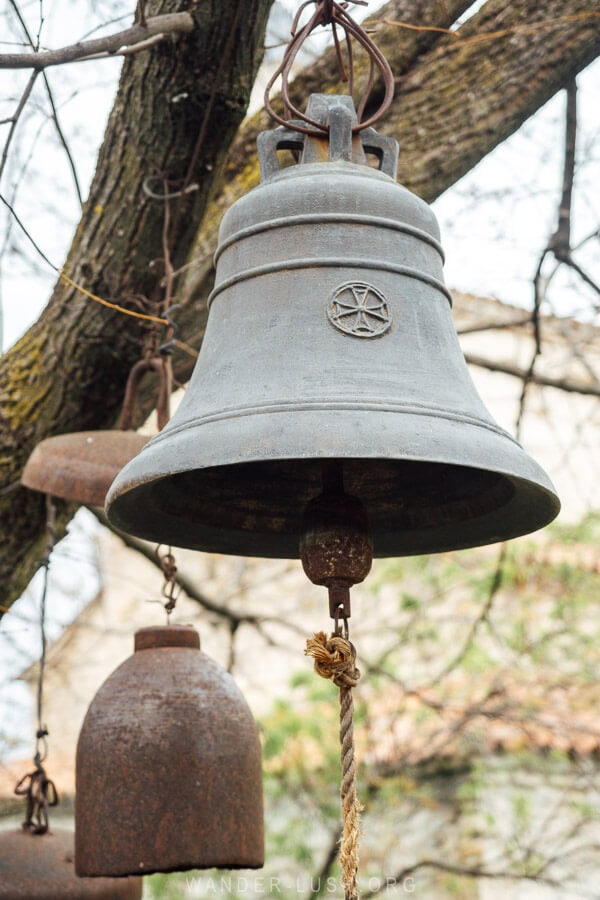 Heavy bells hanging from a tree in front of a monastery in Vazisubani, Georgia.