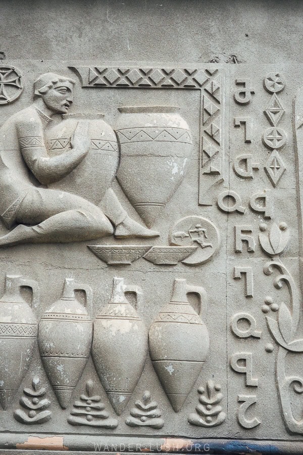 Soviet decorations on the facade of a former museum in Gurjaani showing a man with clay qvevri jars.
