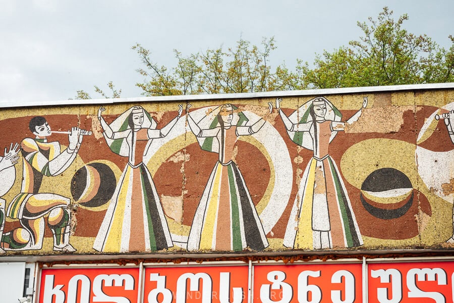 A mosaic panel depicting three female dancers at the former bus station in Gurjaani.