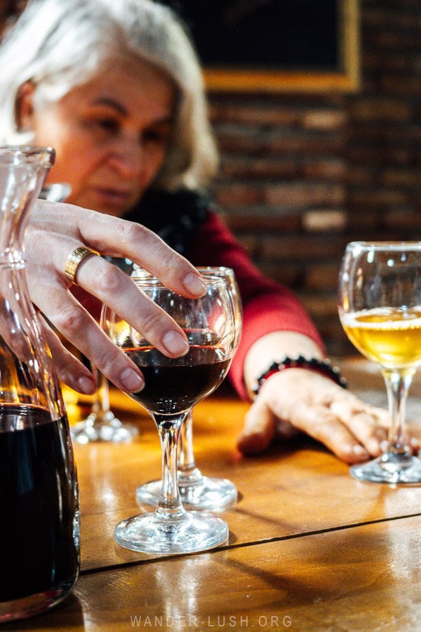 A woman passes a glass of red wine across at table at the Numisi Cellar Museum in Gurjaani.