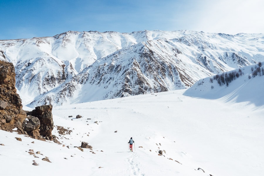 A woman hiking through the snow in the Sioni Valley near Kazbegi, with rock formations all around.