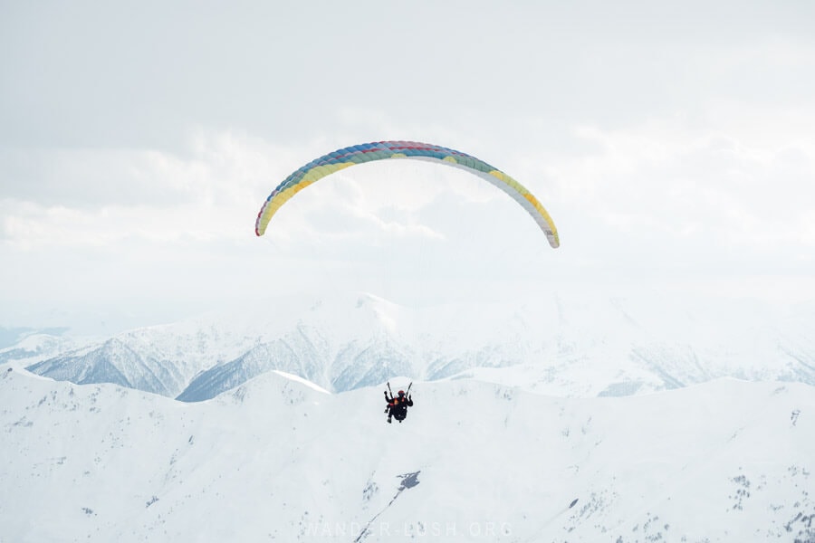 Tandem paragliders sailing into the mountains in Gudauri.