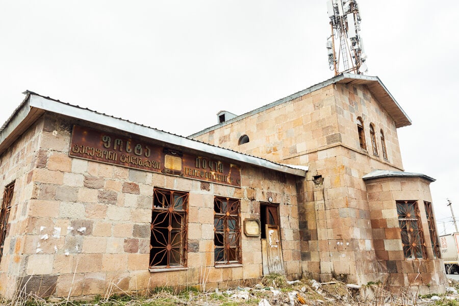 The old Gudauri post office, an old stone building in Gudauri with Georgian and Russian signage.