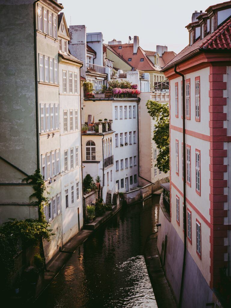 Colorful buildings lining the river in Prague on a sunny afternoon.