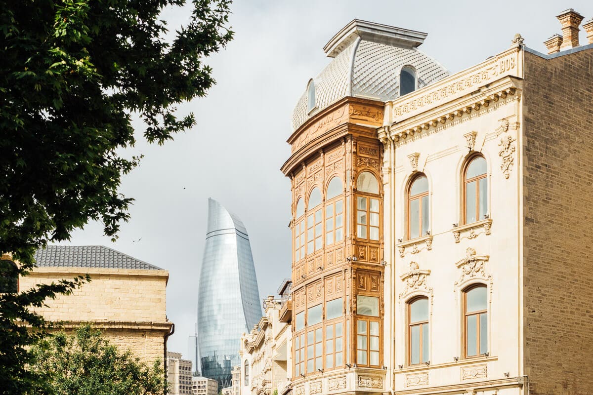 A classic view of Baku with old buildings in the foreground and the Flame Towers in the distance.