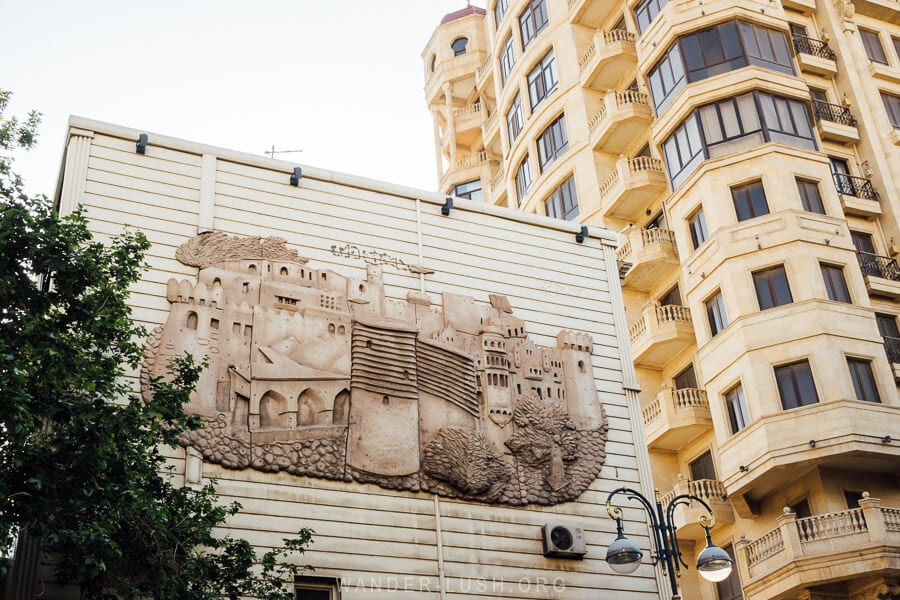 A sculpture of Baku Old City on a wall in front of an apartment building.
