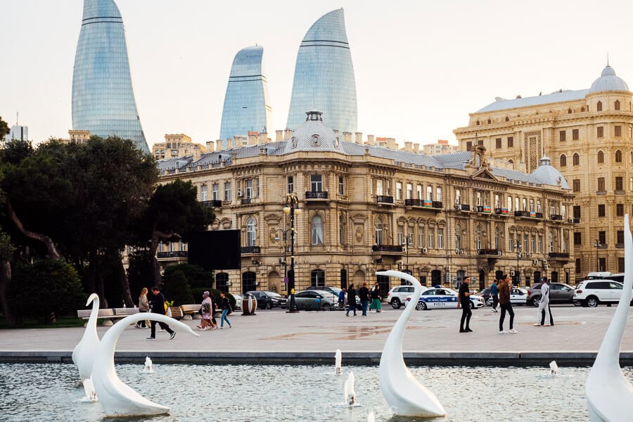 Swans Fountain in Baku, a European-style plaza with a view of the Flame Towers behind a heritage facade.
