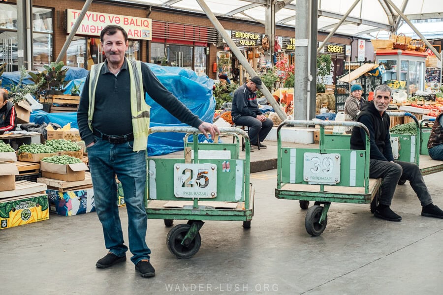 Vendors dressed in high-vis vests pushing carts pose for a photo inside the Yasil Bazaar, a covered green market in Baku Azerbaijan.