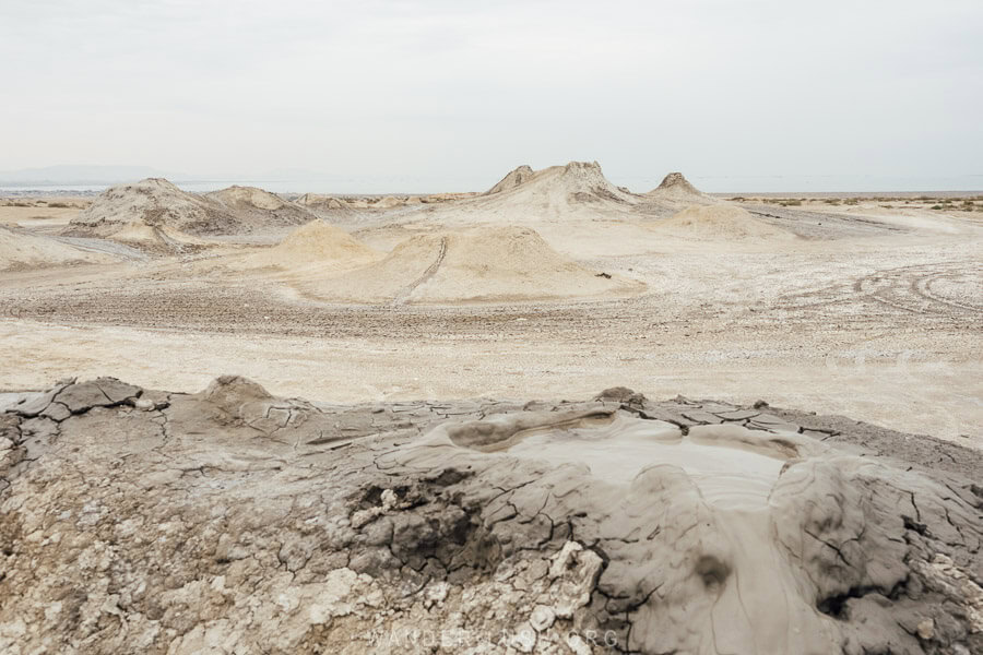 A bubbling mud volcano with more craters in the distance at the Gobustan Mud Volcanoes in Azerbaijan.