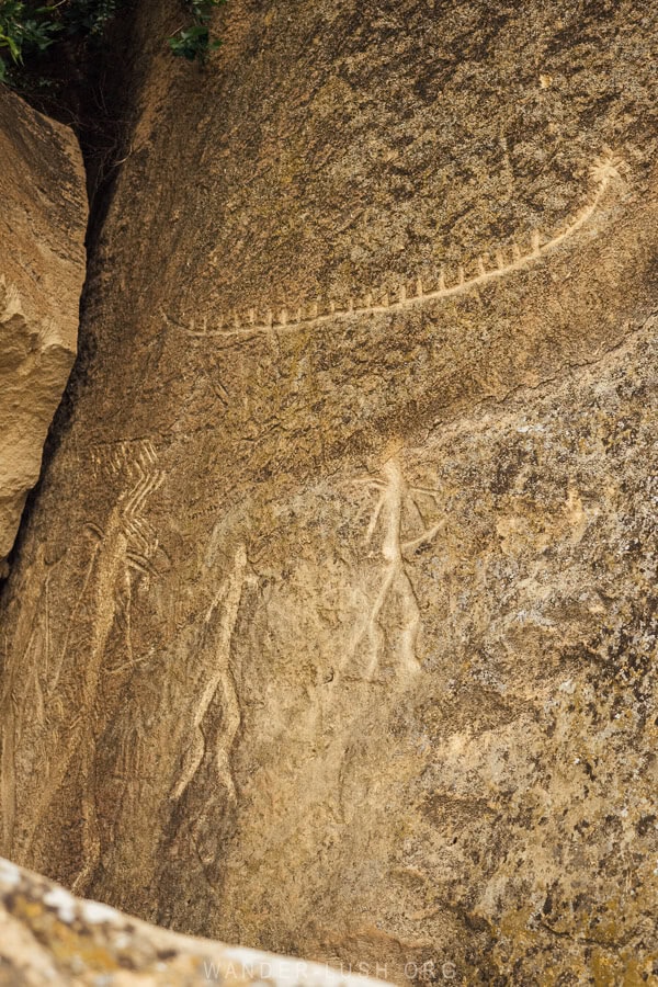Gobustan petroglyphs near Baku depicting human figures and a long boat carved from the rock.