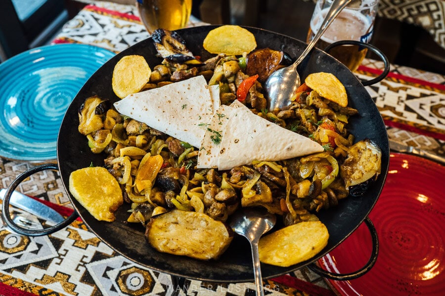 A saj pan on a restaurant table in Baku, filled with meat, vegetables and lavash bread.