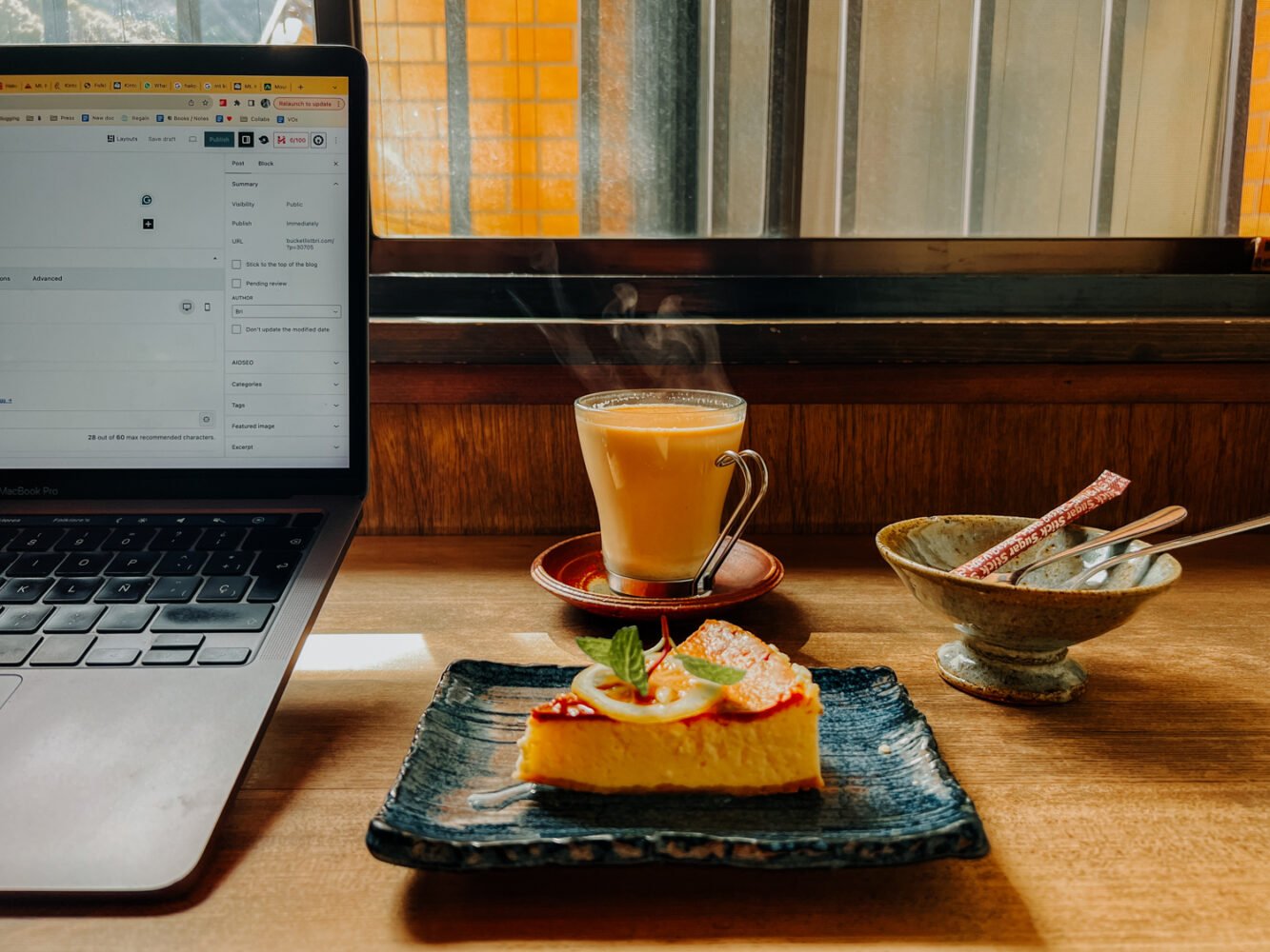 Cozy cafe setting in Hakone with slice of cheesecake, chai latte, and laptop.