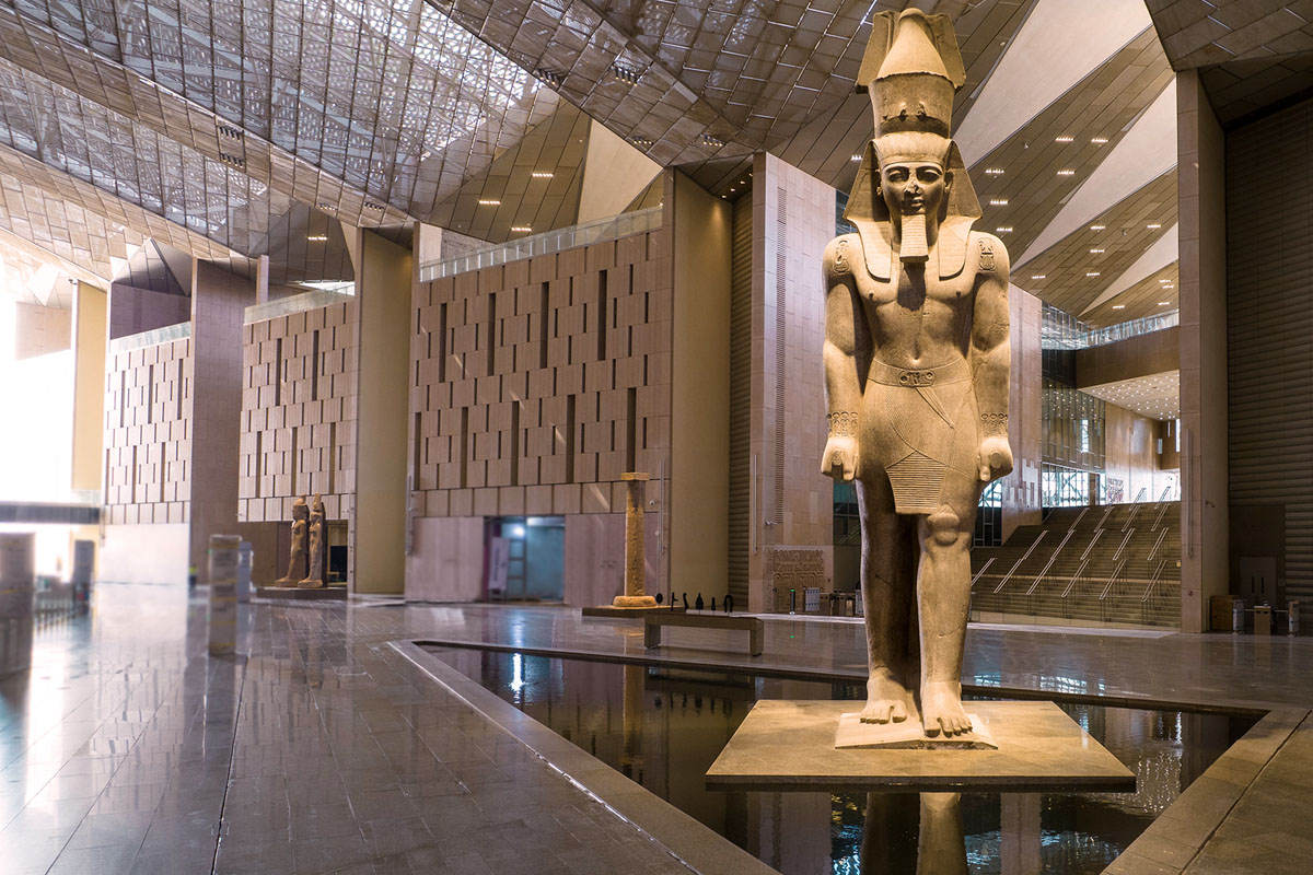 An enormous statue at the Grand Egyptian Museum in Giza. The statue is of Ramses and the surroundings are sleek and modern.