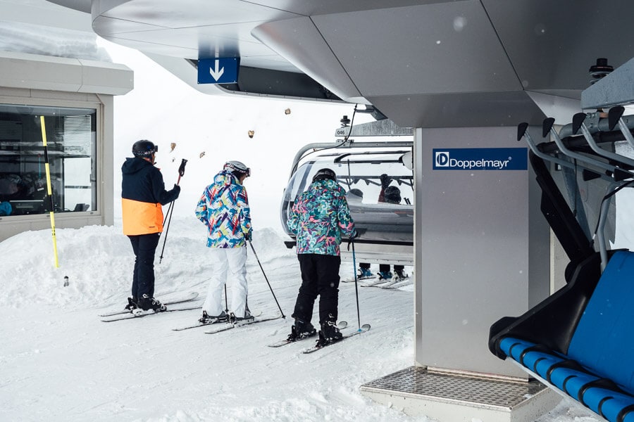Three people boarding a modern chairlift in Georgia.