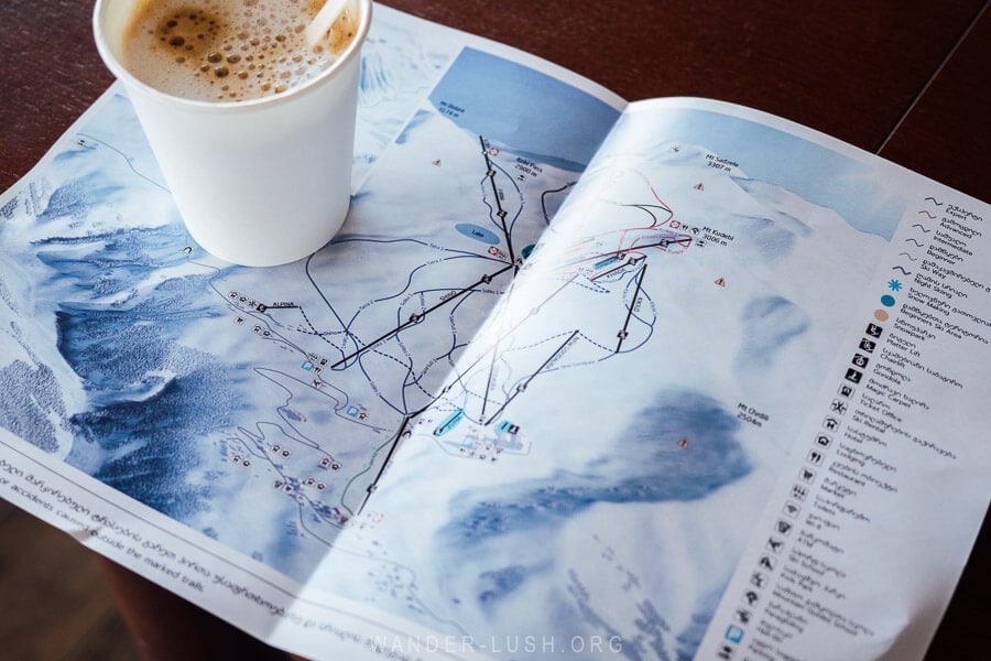 A map of Gudauri ski resort laid out on a cafe table with a paper cup of coffee.